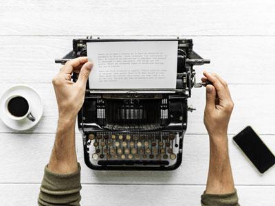Pessoa a escrever uma história numa máquina de escrever