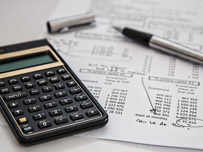 Calculadora, caneta e facturas sobre uma mesa